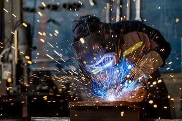 Industrial welder at work with sparks flying — Baked Industries